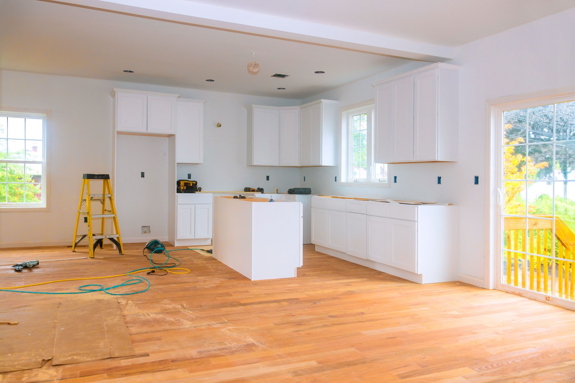 Modern kitchen renovation in progress with new cabinetry and hardwood flooring being installed